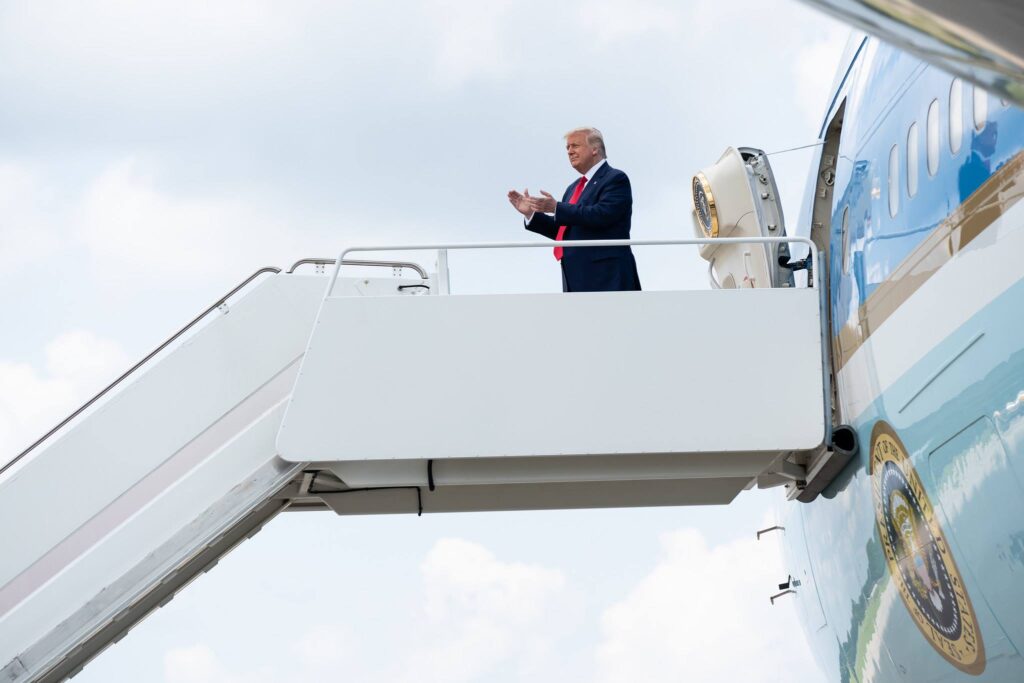 Donald Trump stands on a motorized staircase in front of Air Force One.